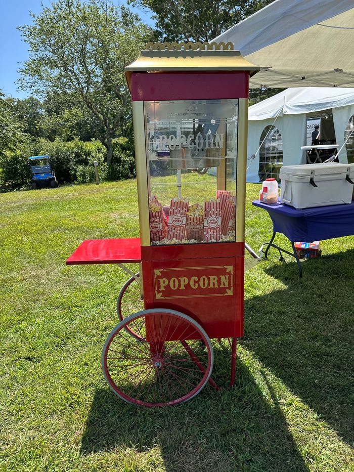 The farm's vintage-style popcorn cart set up on the grass at an event at Lavender Waves Farm