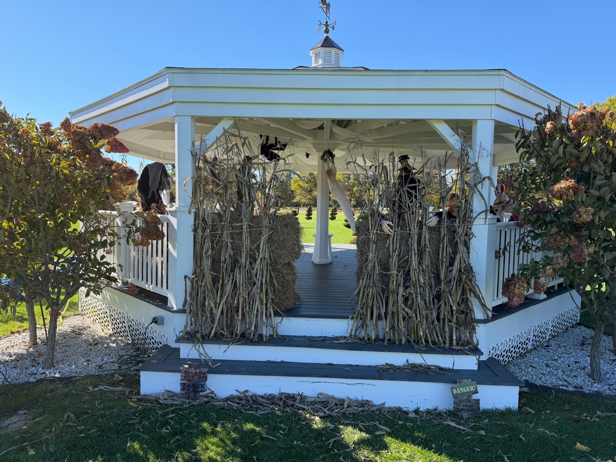 The gazebo dressed as a haunted house, cornstalks and hay bales at the door